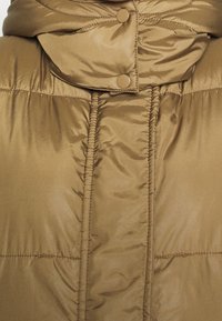 Manteau matelassé couleur fauve avec un col montant, doté de boutons-pression et d'une texture matelassée verticale. Surface lisse et brillante, isolation chaude visible.
