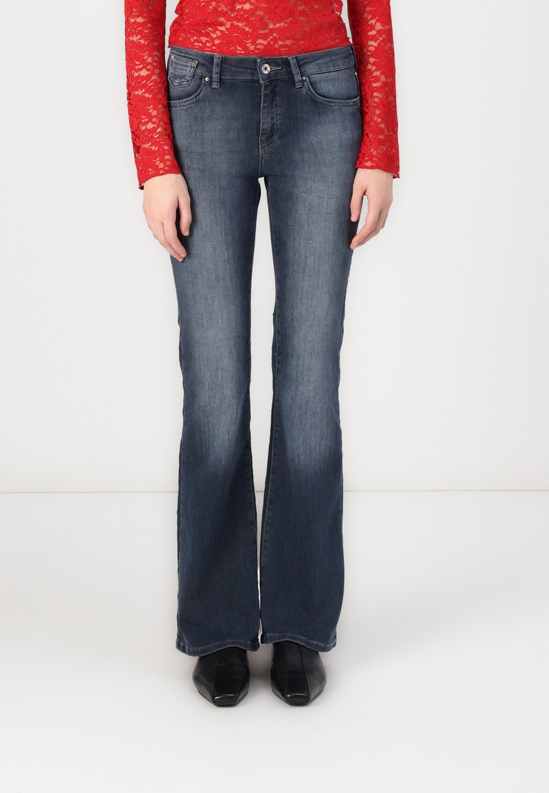 Jeans acampanados de color azul oscuro con un ligero desvanecimiento, hechos de denim; con un diseño de cinco bolsillos y cierre de botón con pasadores para cinturón.