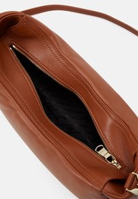 Borsa in pelle marrone con chiusura a zip, superficie texturizzata e fodera in tessuto con un motivo sottile. Spazio interno visibile dall'angolazione.