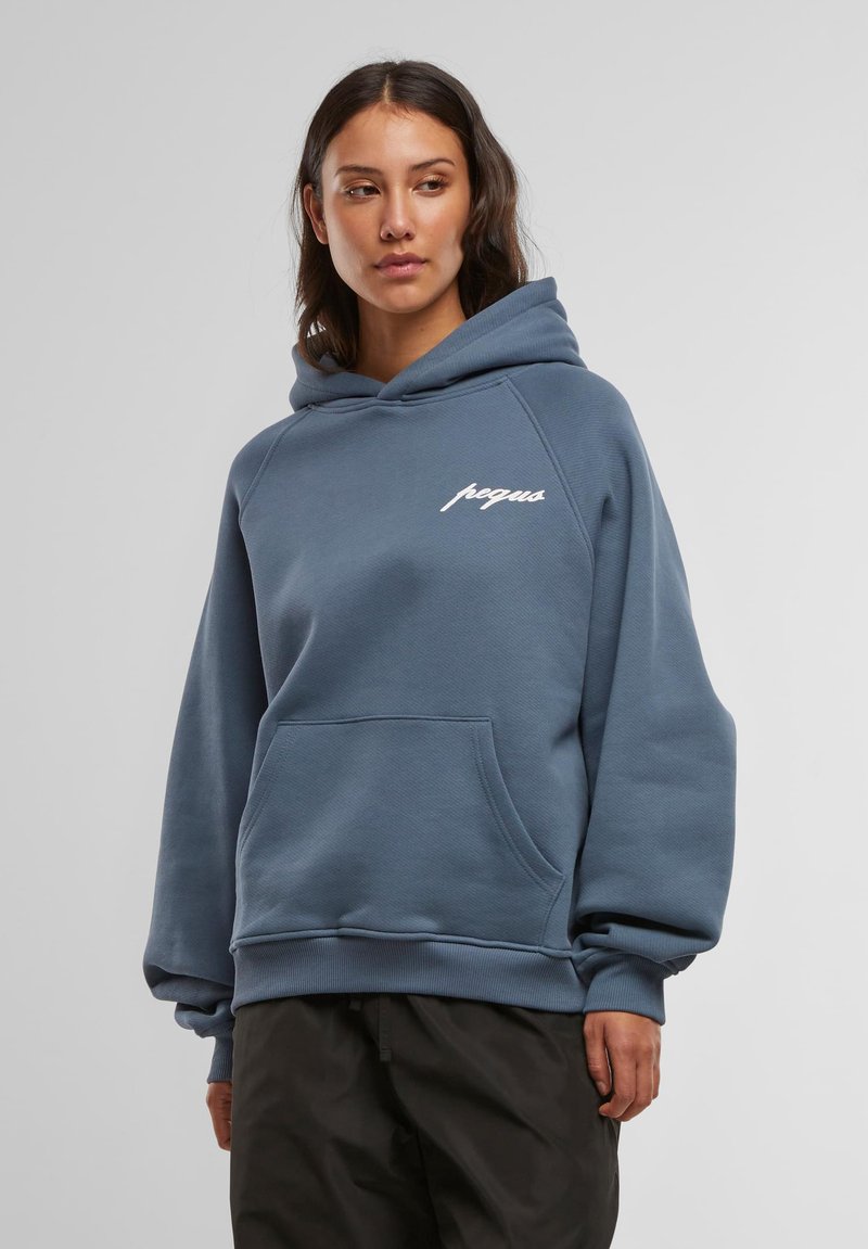 Modrá mikina s kapucňou, predným vreckom, šnúrkou na kapucni a bielym logom na hrudi. Má rebrované manžety a lem, vyrobená z mäkkého materiálu.