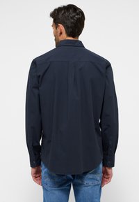 Camicia a maniche lunghe a scacchi blu scuro con colletto classico e polsini abbottonati, realizzata in un tessuto morbido con una vestibilità tagliata.