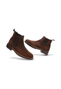 Botas Chelsea de ante marrón con paneles laterales elásticos, tirador, punta redonda y suela de goma texturizada. Sin marcas ni patrones visibles.