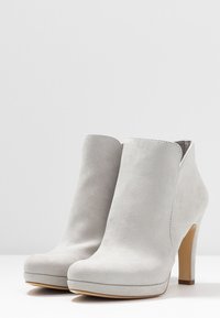 Graue Wildleder-Ankle-Boots mit hohem Absatz, abgerundeter Spitze und Plattform-Design. Die Stiefel haben eine saubere, glatte Textur mit minimaler Naht.