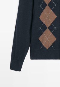 Maglione blu navy con un motivo a diamante in marrone e bianco. Realizzato in tessuto a maglia, con maniche lunghe e polsini a coste.