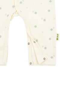 Kremowy kombinezon dla niemowląt z bladozielonym wzorem koniczyny i srebrnymi zatrzaskami wzdłuż szwu krocznego i nogawek.