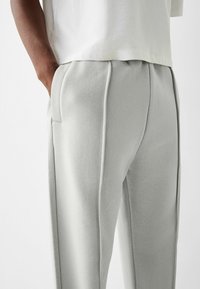 Light gray sweatpants made of soft fabric, featuring a tapered design, elastic waistband, and side pockets for utility.