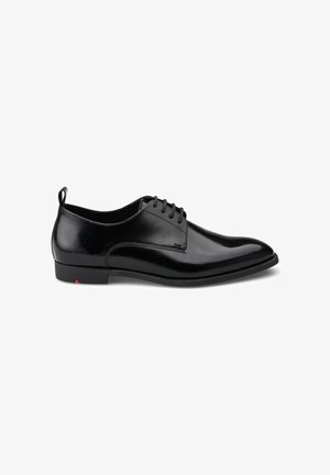 Schwarze Lederhausschuhe mit hochglänzender Oberfläche, spitzem Schuhdesign und Schnürung. Verfügt über einen kleinen roten Akzent an der Ferse.
