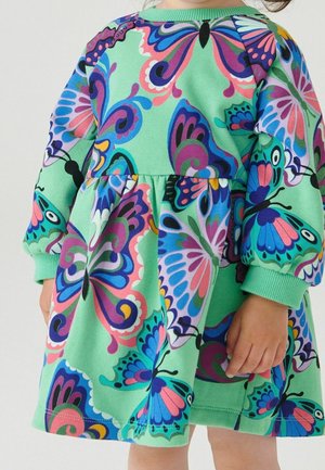 Długo rękawowa, zielona sukienka z kolorowym nadrukiem motyli. Materiał jest miękki, z marszczonym dołem i prążkowanymi mankietami dla zapewnienia wygodnego dopasowania.