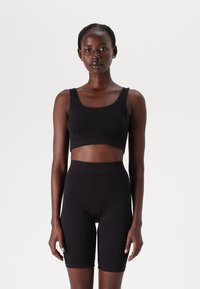 Zwarte sportieve crop top en hoge taille shorts gemaakt van gladde stof. De shorts hebben een subtiele textuur, met een naadloos ontwerp en minimalistische stijl.
