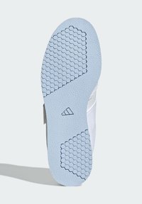 Jasnoniebieska gumowa podeszwa buta z teksturowanym sześciokątnym wzorem, gładkimi krawędziami i logo marki po boku.