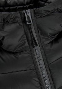 Black puffer jacket close-up, featuring a sturdy zipper, quilted texture, and smooth, lightweight fabric. Reinforced seams visible.