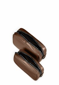 Zwei braune, glänzende Kosmetiktaschen, eine größere und eine kleinere, mit schwarzen Reißverschlüssen, die weißen Text und glatte rechteckige Formen aufweisen.