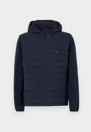 Marineblå hettejakke med quiltet front, glidelåslukking, sidelommer, elastiske mansjetter og liten Tommy Hilfiger-logo på brystet.