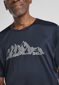 Marineblauw T-shirt met korte mouwen met een wit bergafbeelding en het "Jack Wolfskin" logo. Soepele textuur, ronde hals ontwerp.