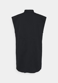 Chemise sans manches noire avec un col haut, affichant un design épuré, une coupe droite et des détails de couture subtils le long du dos.