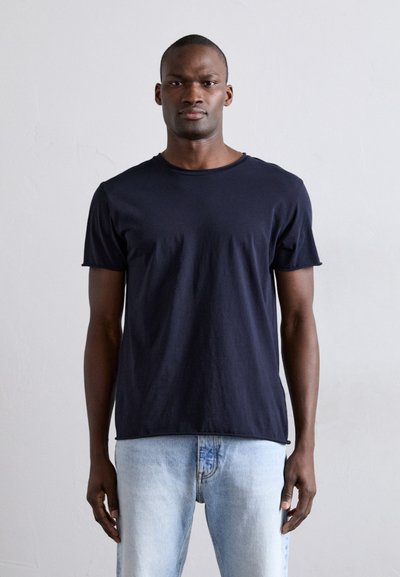 Mørkeblå bomulds T-shirt med korte ærmer, rund halsudskæring og afslappet pasform, parret med lyseblå denimjeans.