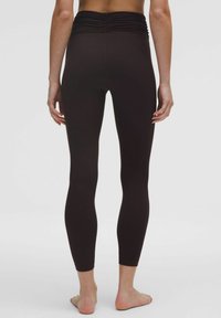Leggings maro cu un elastic strâns la talie. Fabricate dintr-un material neted și elastic. Designul prezintă o croi ajustat și picioare lungi.