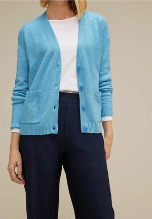 Cardigan bleu clair en tissu doux, doté d'accents côtelés, d'un col en V, de deux poches avant et de quatre boutons bleus sur le devant.