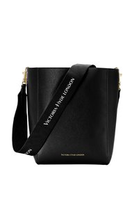 Černá kožená kabela ve tvaru kyblíku se strukturovaným tvarem, zlatými kovovými prvky a látkovým popruhem s nápisem "VICTORIA HYDE LONDON" v bílé barvě.