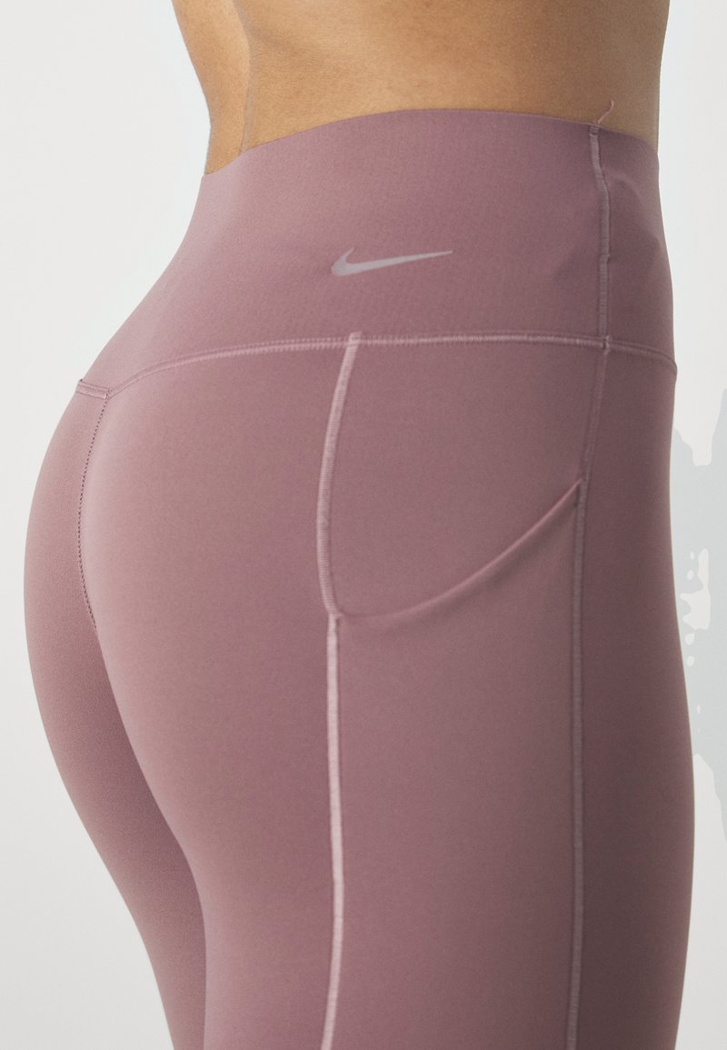 Leggings a vita alta in tessuto mauve, con una tasca laterale discreta, cuciture a contrasto e un piccolo logo grigio vicino alla vita.