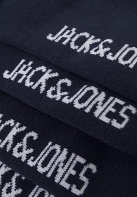 Navy-blauer Strickstoff mit abwechselndem weißen Text "JACK&JONES." Das Design weist eine weiche Textur und ein einheitliches Muster auf.