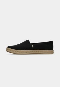 Svarta slip-on skor med överdel i canvas och sula i naturligt jute-rep, med en stickad design och logodetalj på sidan.
