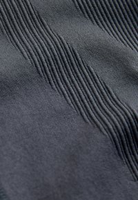 Tessuto tessile in grigio scuro, con un motivo strutturato che alterna sezioni lisce e rigate. Aspetto morbido e intrecciato.