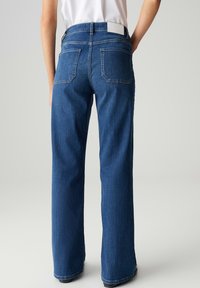 Lichte-blauwe denim jeans met wijd uitlopende pijpen, hoog in de taille, achterzakken en een wit label op de tailleband. Zachte textuur met versterkte stiksels.