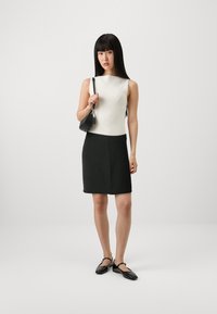 Top sans manches blanc à côtes, jupe noire ajustée et chaussures vernies noires. Design simple avec une texture lisse et des lignes épurées.