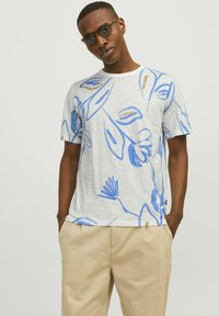 Kortärmad t-shirt i ljusgrått tyg med blå och bruna abstrakta bladmönster. Rund halsdesign med avslappnad passform.