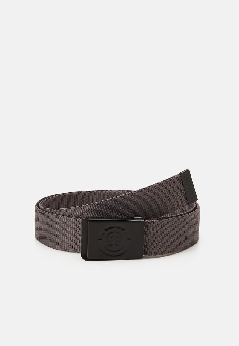 Cinturón de nylon tejido en gris con una hebilla rectangular negra mate que presenta un logo circular. Los extremos están ligeramente deshilachados, y la correa es suave y flexible.