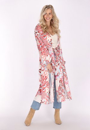 Lang, vloeiende kimono in crème met rode en blauwe bloempatronen. Lichtgewicht stof, wijde mouwen en open voorkant. Gekocht boven een crèmekleurig top en blauwe jeans.