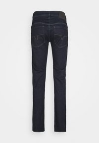 Mörka denimjeans med rak ben design, två bakfickor med sömnadsdetaljer och en svart varumärkeslapp vid midjan.