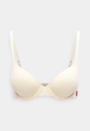 Jasnobeżowy biustonosz z formowanymi miseczkami, regulowanymi ramiączkami i zapięciem na haftkę. Miękki materiał o minimalistycznym designie z małą metką po boku.