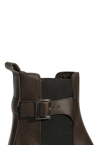 Bruine leren enkelboot met elastische pan, platte hak en metalen gesp-accent. Gladde textuur en schoon, minimalistisch ontwerp.