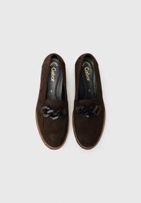 Braune Wildleder-Loafer mit einer dekorativen schwarzen Kettenakzent und Nahtdetails. Das Innere hat eine gepolsterte Einlegesohle für zusätzlichen Komfort.