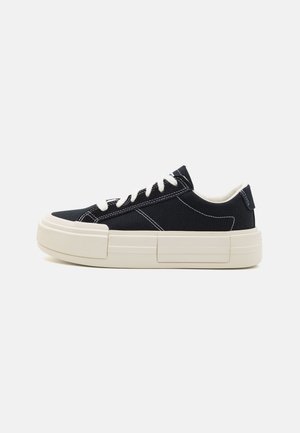 Sneakers neri in tela con lacci e cuciture bianchi. Presentano una suola bianca spessa e texturizzata con un design segmentato unico.