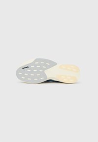 Shoe sole facing up showing white, beige, and gray rubber sections with Continental logo on a smooth gray background.