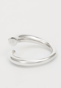 Pulsera de acero inoxidable con un diseño suave y redondeado; presenta un pequeño logo grabado en un extremo.