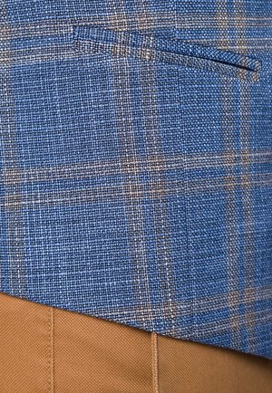 Niebieska tkanina w kratkę o teksturowanej powierzchni, zawierająca ciemne i jasne nici. Zawiera boczną kieszeń, połączoną z jasnobeżowym materiałem poniżej.