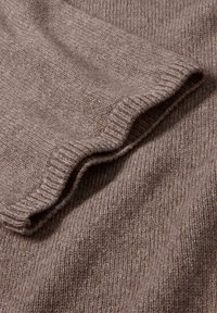 Maglione di colore marrone a maglia con un colletto e orlo a costine. La texture è morbida e leggermente pelosa, mostrando un motivo variegato e sottile.