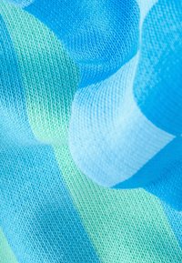 Gros plan d’un tissu tricoté avec des rayures douces bleues, turquoises et vertes montrant la texture détaillée des mailles et des plis délicats.