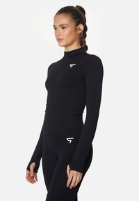 Schwarzes langärmliges Zip-Up-Oberteil aus dehnbarem Stoff, mit einem hohen Kragen und Daumenlöchern an den Bündchen. Weiße Logoakzente auf der Brust.