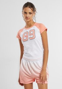 Tricou sport cu mânecă scurtă, alb și piersică, cu numărul 89, asortat cu pantaloni scurți ombre în nuanța piersicii. Ambele confecționate din material moale și ușor.