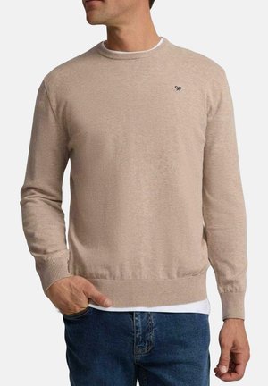 Suéter de punto beige con mangas largas, escote redondo y puños acanalados. Presenta un pequeño logo en el lado izquierdo del pecho y un diseño ajustado.