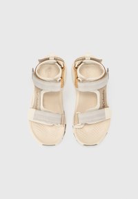 Beige and gray sandals with two Velcro straps, textured footbed, and cushioned heel. Slightly curved sole with rubber accents for grip.