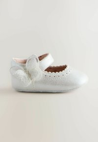 Balti ādas baleta zābaki ar viļņotu malu, siksniņu un dekoratīvu tauriņa akcentu sānos. Gluda tekstūra, apaļa purna forma.