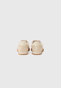Beige ruskinnsko med glatt finish, avrundet form, gummis�åle og subtil sømdetalj ved hælen og sidene.