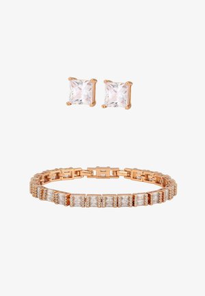 Braccialetto d'oro con pietre rettangolari trasparenti e orecchini a bottone abbinati con pietra quadrata trasparente, mostrati su sfondo bianco.