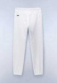 Witte sportbroek gemaakt van zachte stof, met een elastische tailleband en taps toelopende boorden. Een klein logo staat vlakbij de tailleband.